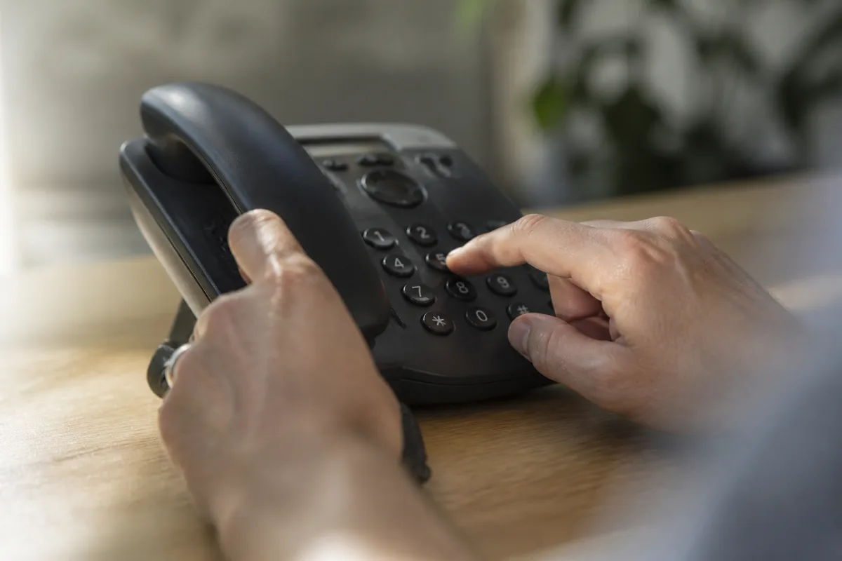 Mains composant un numéro sur le clavier d&rsquo;un téléphone de bureau